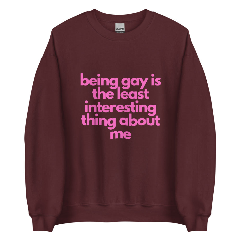 This is a pride apparel crewneck sweatshirt. It is maroon and has "being gay is the least interesting thing about me" written across the front in pink letters.