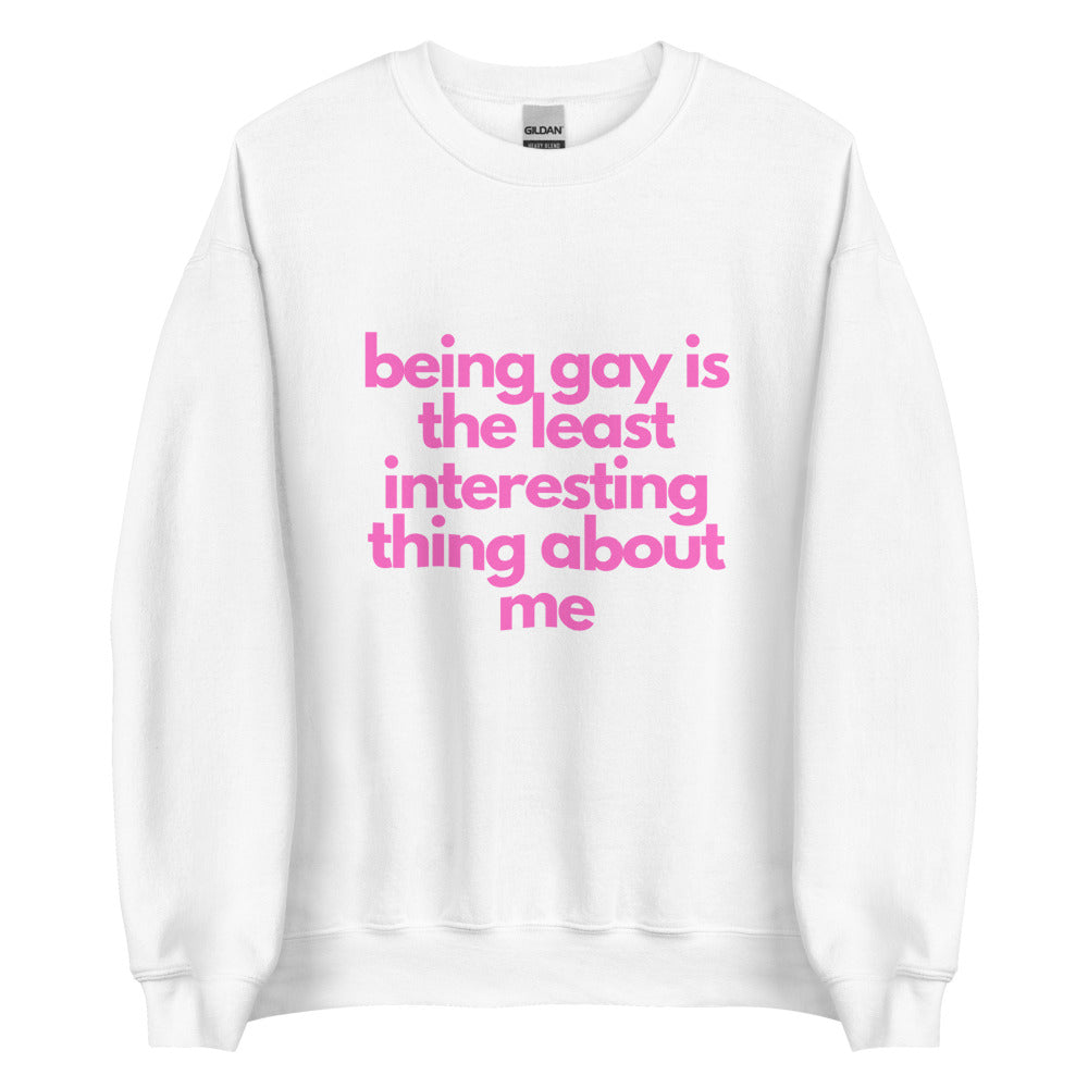 This is a pride apparel crewneck sweatshirt. It is white and has "being gay is the least interesting thing about me" written across the front in pink letters.